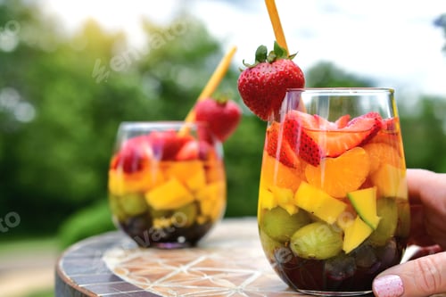 Preview: Glasses of colorful rainbow sangria, summer cocktail fruit alcohol drink outside.