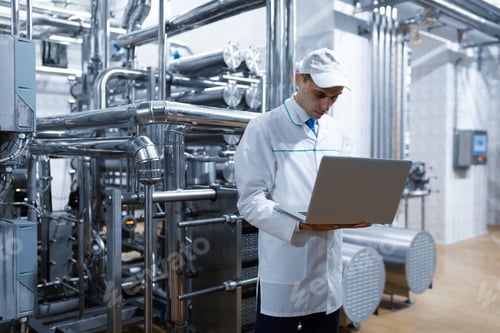 Preview: Technologist with a laptop in his hands at the dairy plant