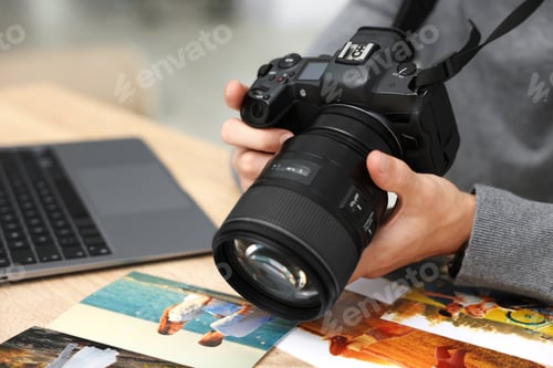 Preview: Professional photographer with camera working at wooden table in studio, closeup