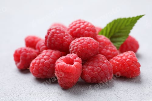 Preview: Delicious fresh ripe raspberries with green leaf on light grey table