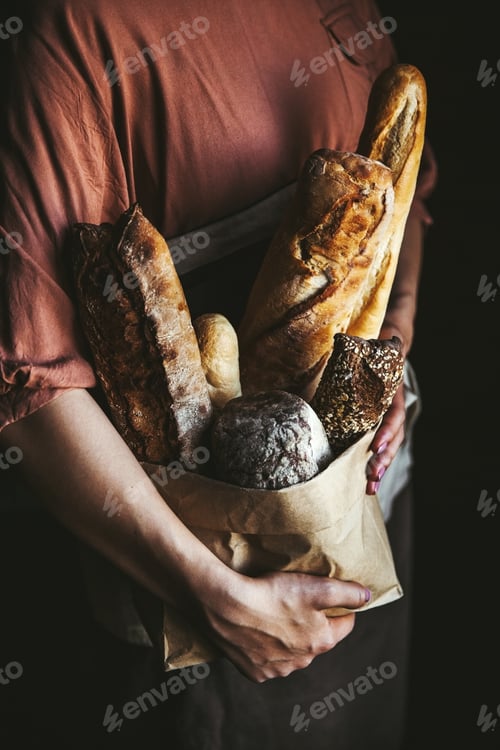 Preview: French baguettes in female hands on a black background. homemade baking