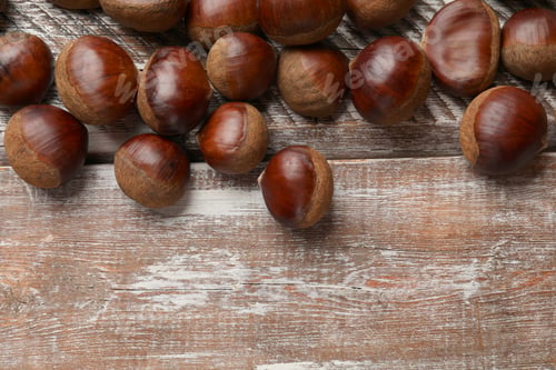 Preview: Sweet fresh edible chestnuts on wooden table, top view. Space for text
