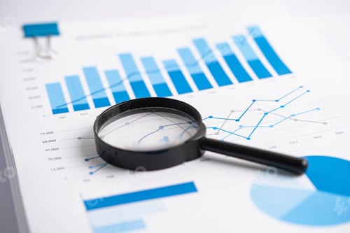 Preview: Magnifying glass on charts graphs paper.