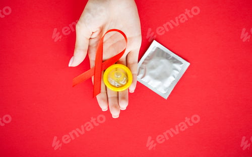 Preview: Close Up woman hand holding red ribbon HIV, world AIDS day awareness ribbon.