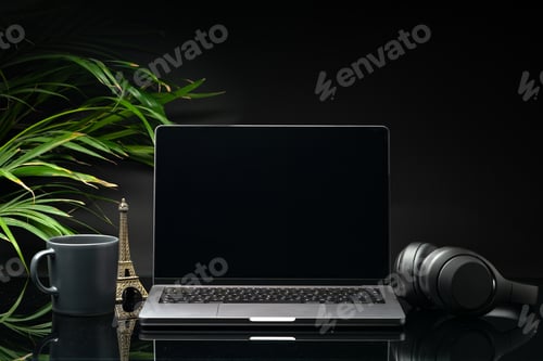Preview: Laptop with black screen on working desk with cup and earphones on black background