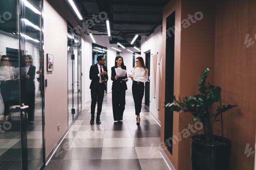 Preview: Group of multiethnic coworkers discussing papers in hallway