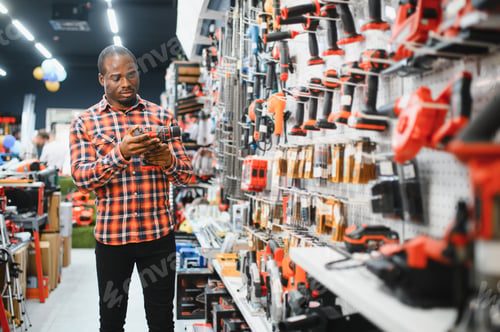 Preview: African americam man buying modern electric drill while standing in tool.