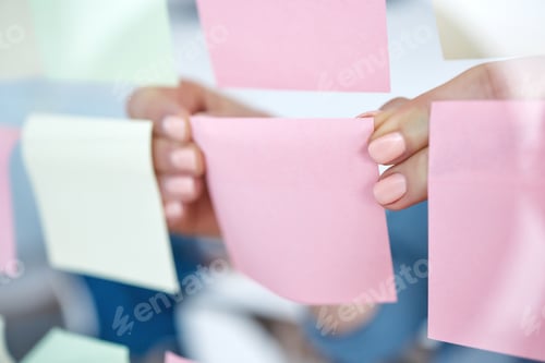 Preview: Closeup of unknown business woman using sticky notes on a transparent board to brainstorm in the of