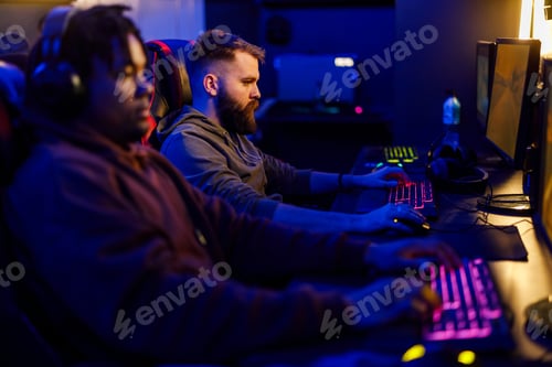 Preview: Bearded male gamer playing video games on a computer in a gameroom