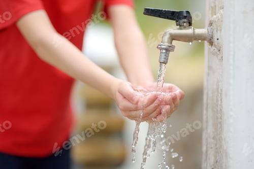 Preview: Closeup photo of child washing hands in a city fountain.