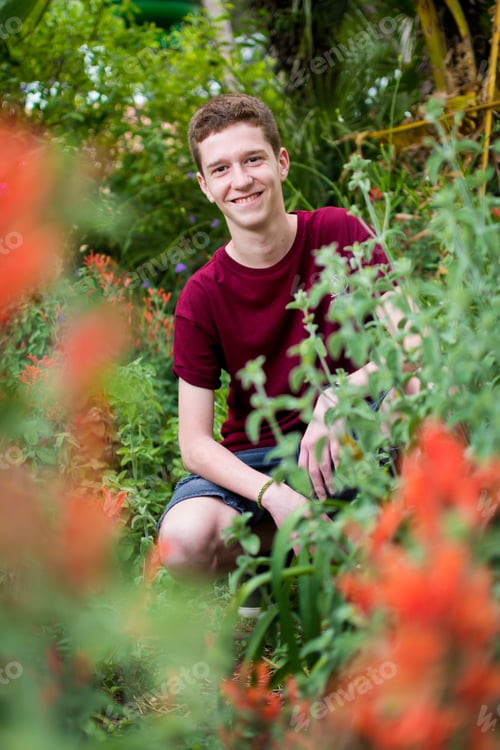 Preview: Red-haired teenager looking between plants in a purple shirt.