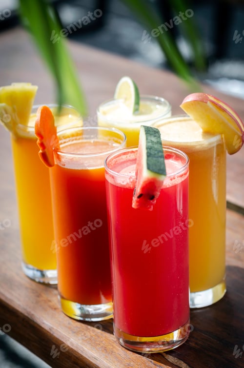 Preview: mixed fresh organic fruit juices glasses on sunny garden table