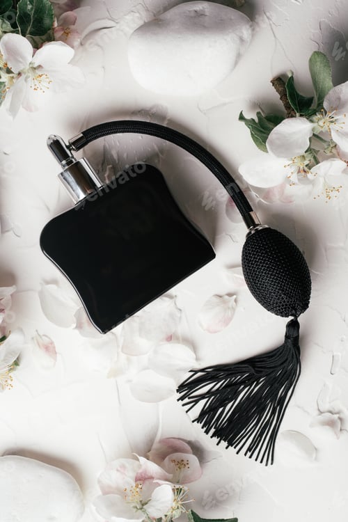 Preview: Black bottle eau de toilette or perfume with long tassel spray pomp on background of apple flowers