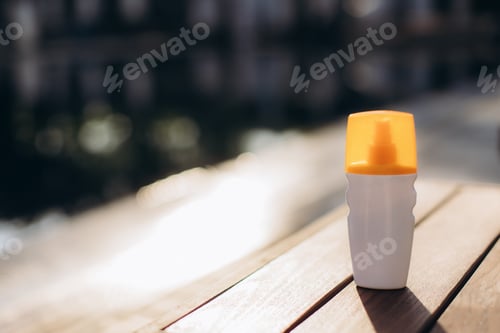 Preview: Sunscreen spray bottle resting on wooden table in sunlight