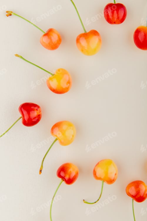 Preview: top view of yellow and red cherries on white background