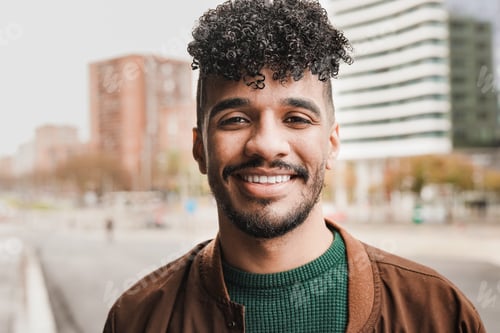 Preview: Young african man smiling on camera with city in background