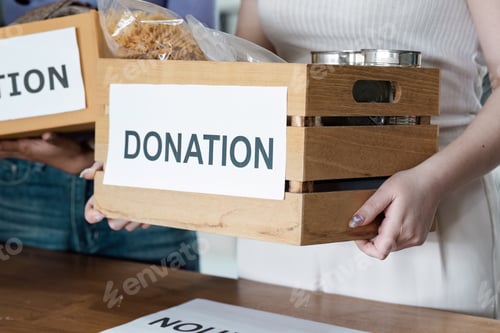 Preview: Woman holding a wooden donation box filled with food items.