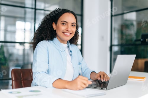 Preview: Beautiful positive multiracial curly haired woman in a shirt, employee of a company, software