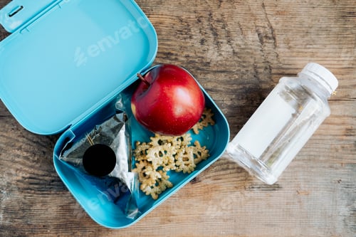 Preview: Asian student's lunchbox of onigiri,chips and apple with bottle of water,On wooden background