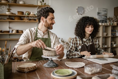 Preview: Couple sculpting clay together during pottery workshop in studio