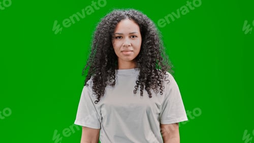 Preview: Young and beautiful African American woman staring at the camera in front of a green wall