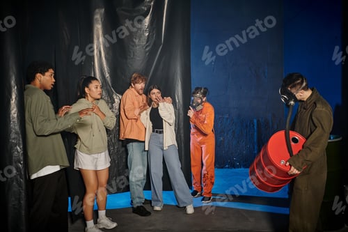 Preview: scared interracial friends looking at people in ppe suits and gas masks in escape room, mystery