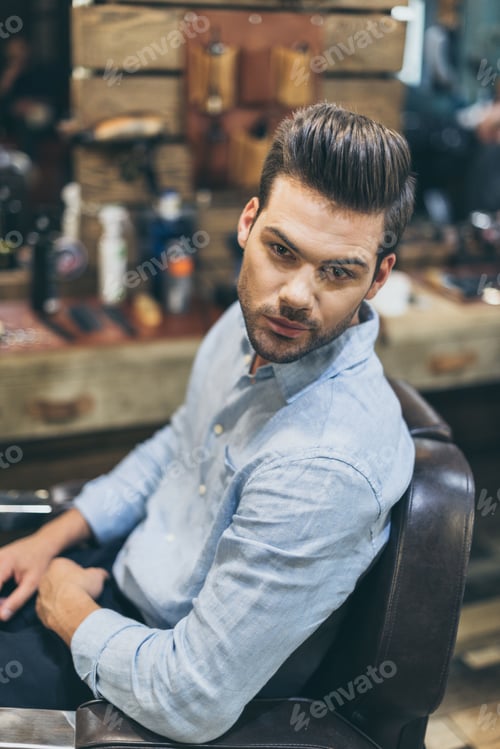 Preview: Portrait of handsome caucasian man with fashionable hairstyle at barber shop