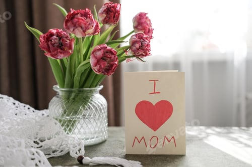 Vista previa: Un ramo de tulipanes en un jarrón y una tarjeta con el texto «Quiero a mamá». Concepto del día de la madre