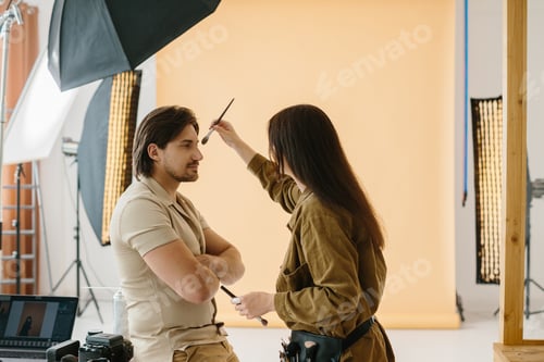 Preview: Make-up artist working during a photo session while preparing the look for the model
