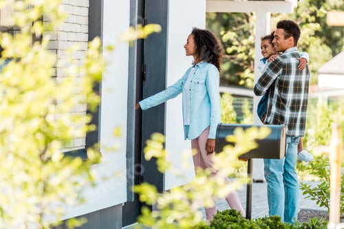 Preview: selective focus of african american family walking into new house while father holding kid