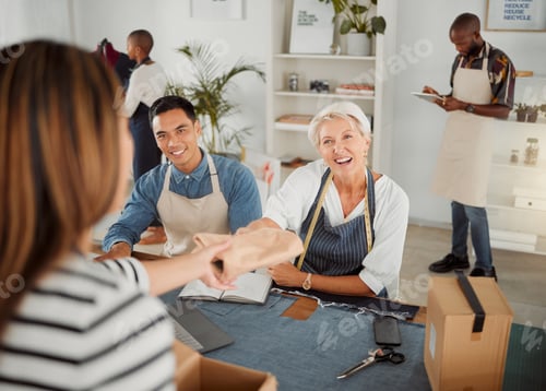 Preview: Joyful mature caucasian clothing designer talking and giving a customer a package in a shop at work