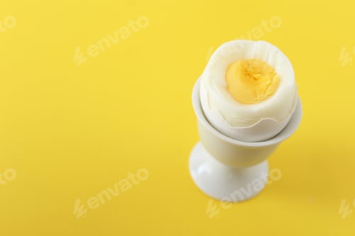 Preview: Yellow background with egg cup and boiled egg. Copy space.