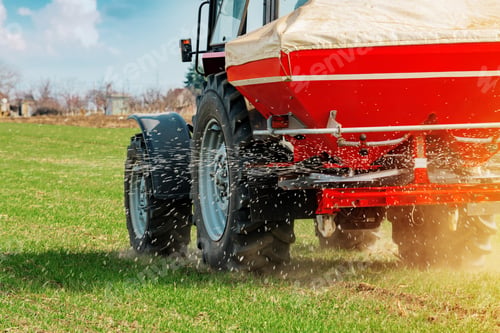 Preview: Agricultural tractor fertilizing wheat crop field with NPK