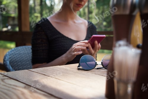 Preview: Woman Using Phone at a Wooden Table