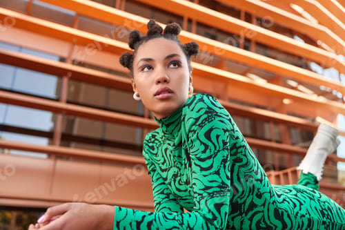 Preview: Horizontal shot of pretty young woman with hair buns applies blue eyeliner dressed in green costume