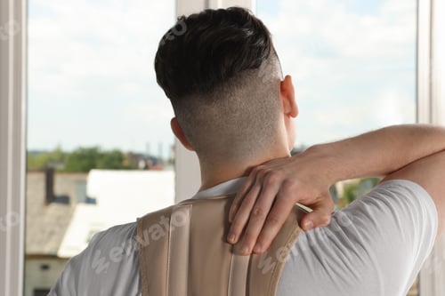 Preview: Man with orthopedic corset near window indoors, back view