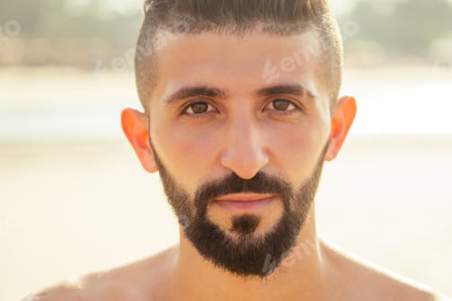 Preview: Young handsome indian man taking a rest after does push-ups on the beach
