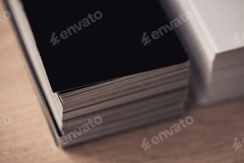 Preview: selective focus of black and white business cards stacked on wooden surface