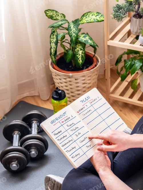 Preview: Woman reviewing her workout plan while organizing a weekly fitness routine