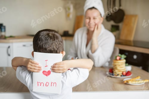 Vista previa: El hijo regala a su madre una tarjeta para el Día de la Madre. Mañana es una sorpresa para mamá con tortitas.