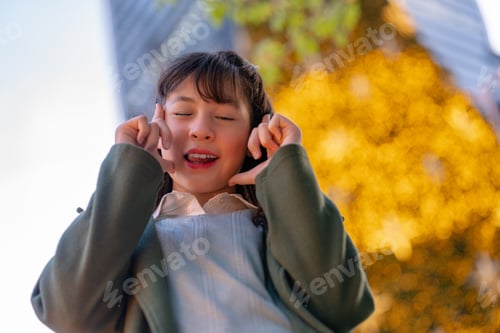 Preview: A joyful young girl in a green coat making playful expressions