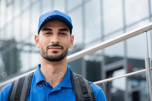 Preview: Arabian courier with backpack looking at camera outdoors