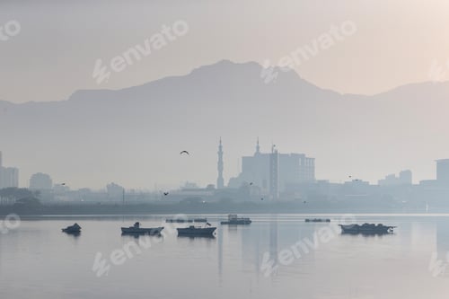 Preview: Foggy morning in Ras Al Khaimah Corniche with boats in the sea and birds flying around