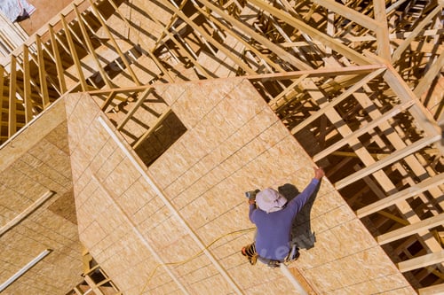 Preview: Carpenter with nailing plywood on roof of the house
