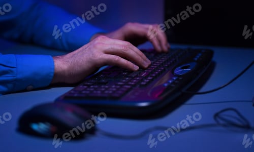 Hands Typing on Keyboard in Dim Blue Light