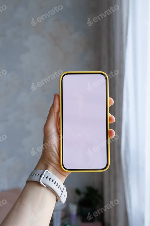 Preview: Close-up of human hand holding black white-screen mobile phone in interior background. mockup
