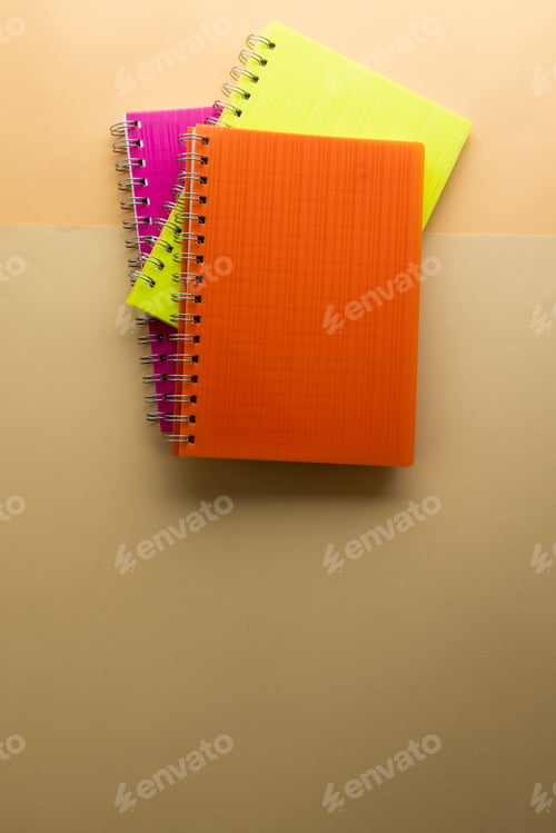Preview: Multi coloured notebooks and copy space on orange background