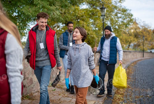 Preview: Diverse group of happy volunteers walking with tools to do street clean up, community service