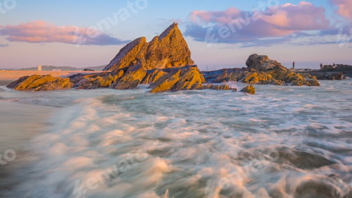 Preview: Burst of bright sunshine illuminating the rocky shoreline of an idyllic beach