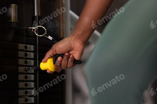 Preview: Woman exercising using weights machine in a gym